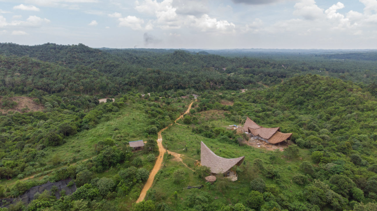 An aerial view of Leuser Nature School with its bamboo buildings surrounded by forest.